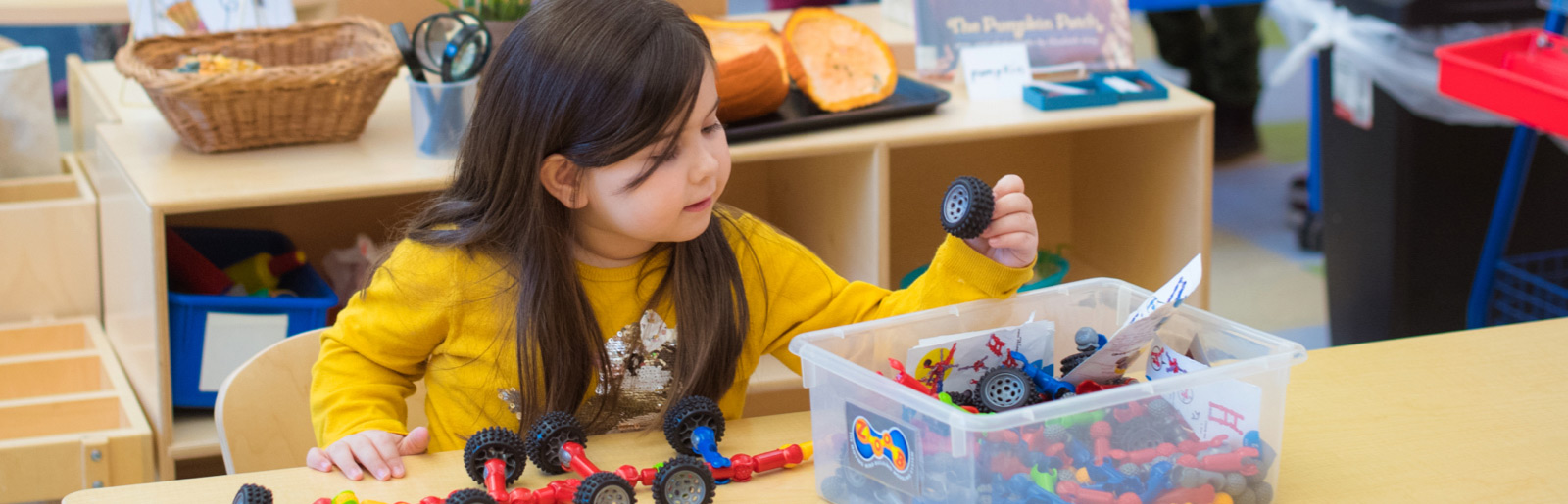 girl looking through a box of toys 