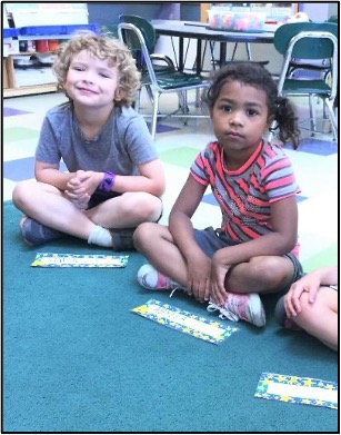two children looking at the camera while sitting on a carpet