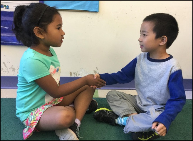 two children greeting each other with a handshake