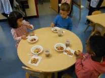 children sit around a table for lunch time