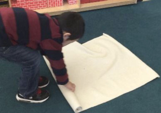 child rolling up canvas mat