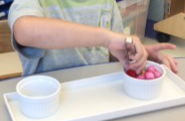 child transferring colored balls from one bowl to another