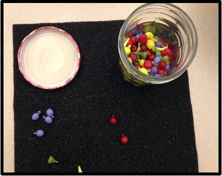 colored sorting fruit manipulatives in a open jar on a place mat