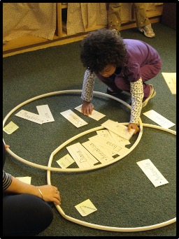 child placing name cards inside hoops on floor