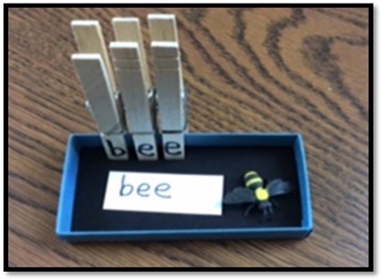 tray with word card, item, and clothes pins with letters to build the word