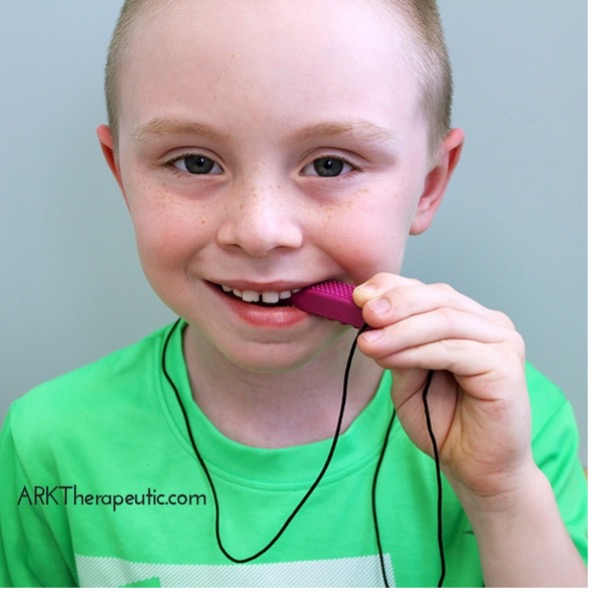 A boy biting a therapeutic necklace.