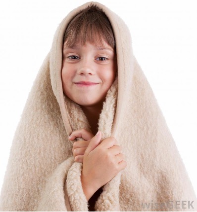 A boy with a soft fuzzy blanket smiling.