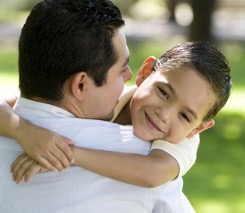 An boy hugging an adult and smiling.