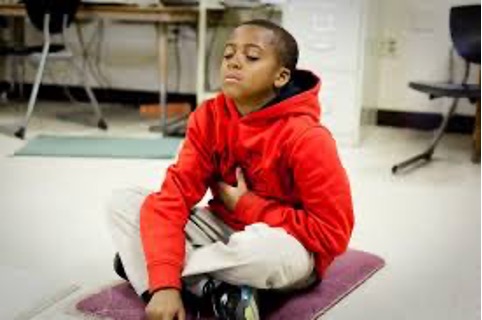 Boy sitting on a cushion cross legged and breathing.