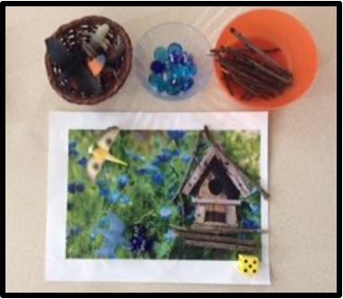 Birdhouse scene with dice, glass gems, sticks and toy birds