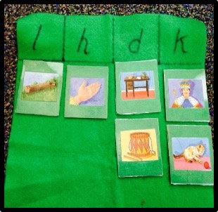 a piece of cloth labeled with letters "l", "h", "d", and "k" at the top and pictures sorted below according to initial sound.