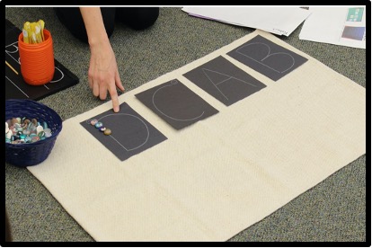 letters written on black paper with child placing gems along the lines of the letter