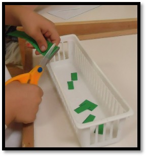 Child snipping paper into a container