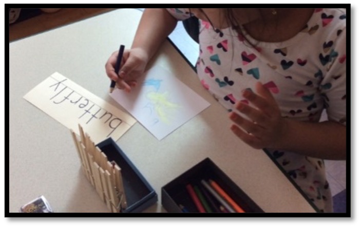 Child labeling their drawing using a vocabulary card