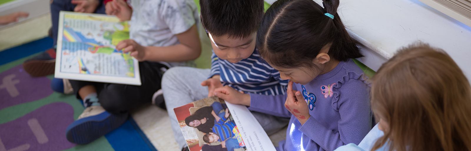 Children sitting on ground sharing books